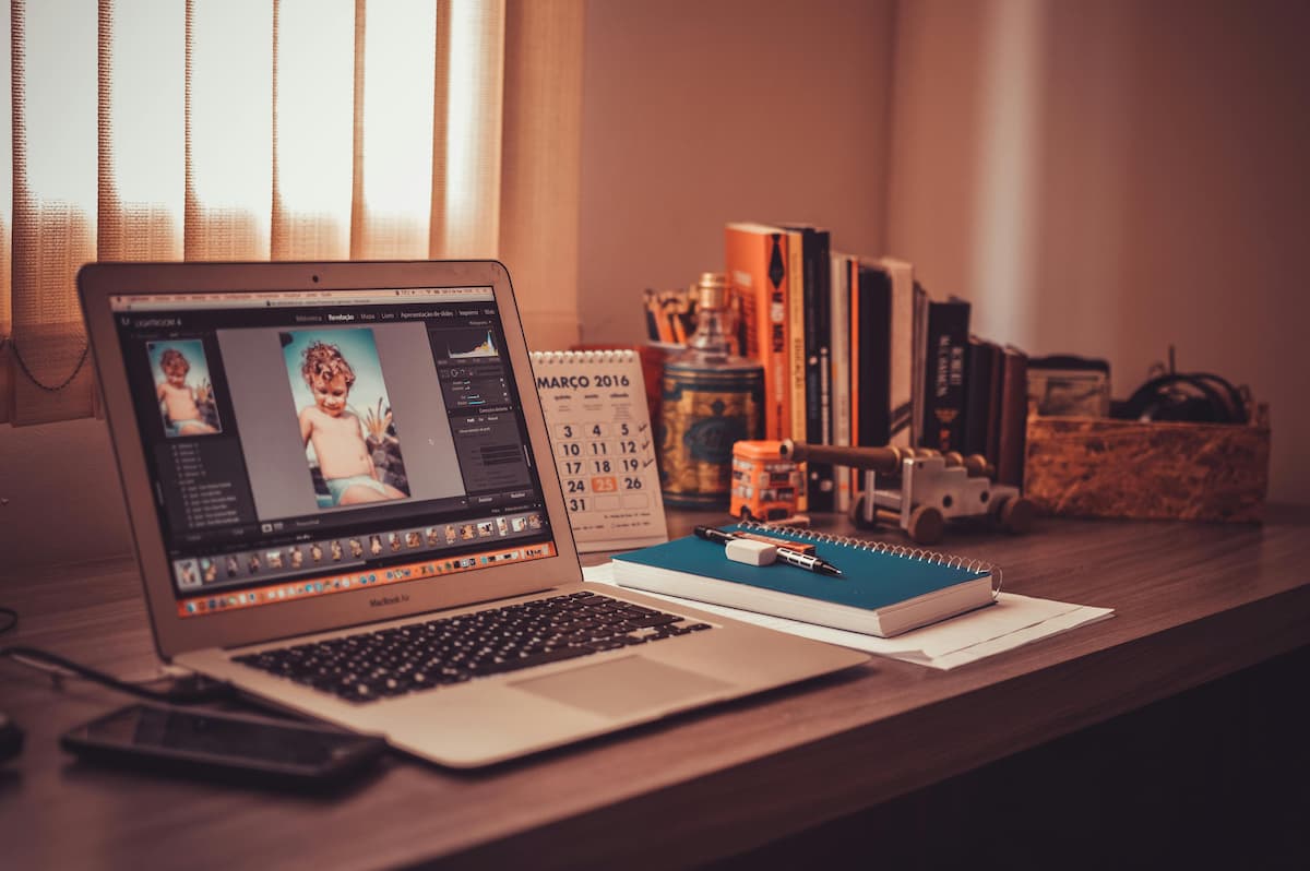 A laptop on a desk with a photo of a child.
